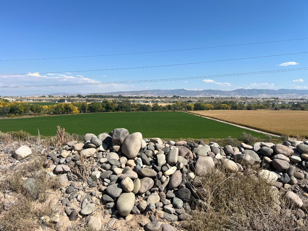 A pile of rocks on top of a hill with a field in the background.
