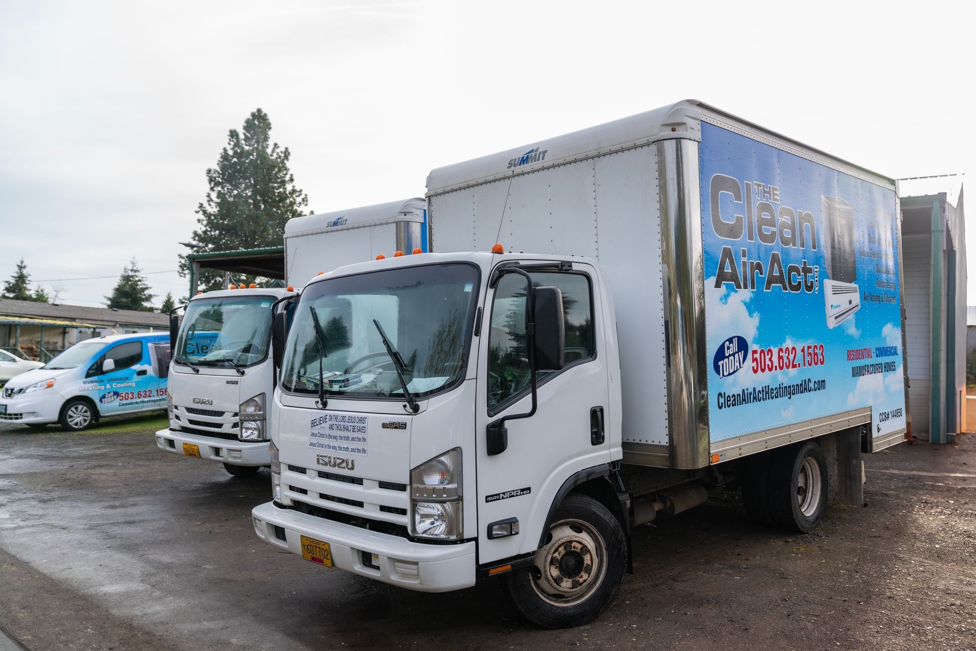 Three The Clean Air Act trucks are parked next to each other on the side of the road.