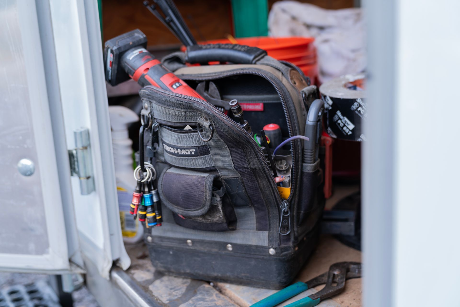 A tool bag with a hose attached to it is sitting in a closet.