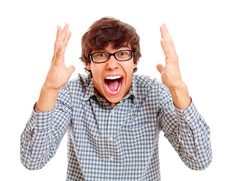 A young man with glasses is screaming with his mouth open