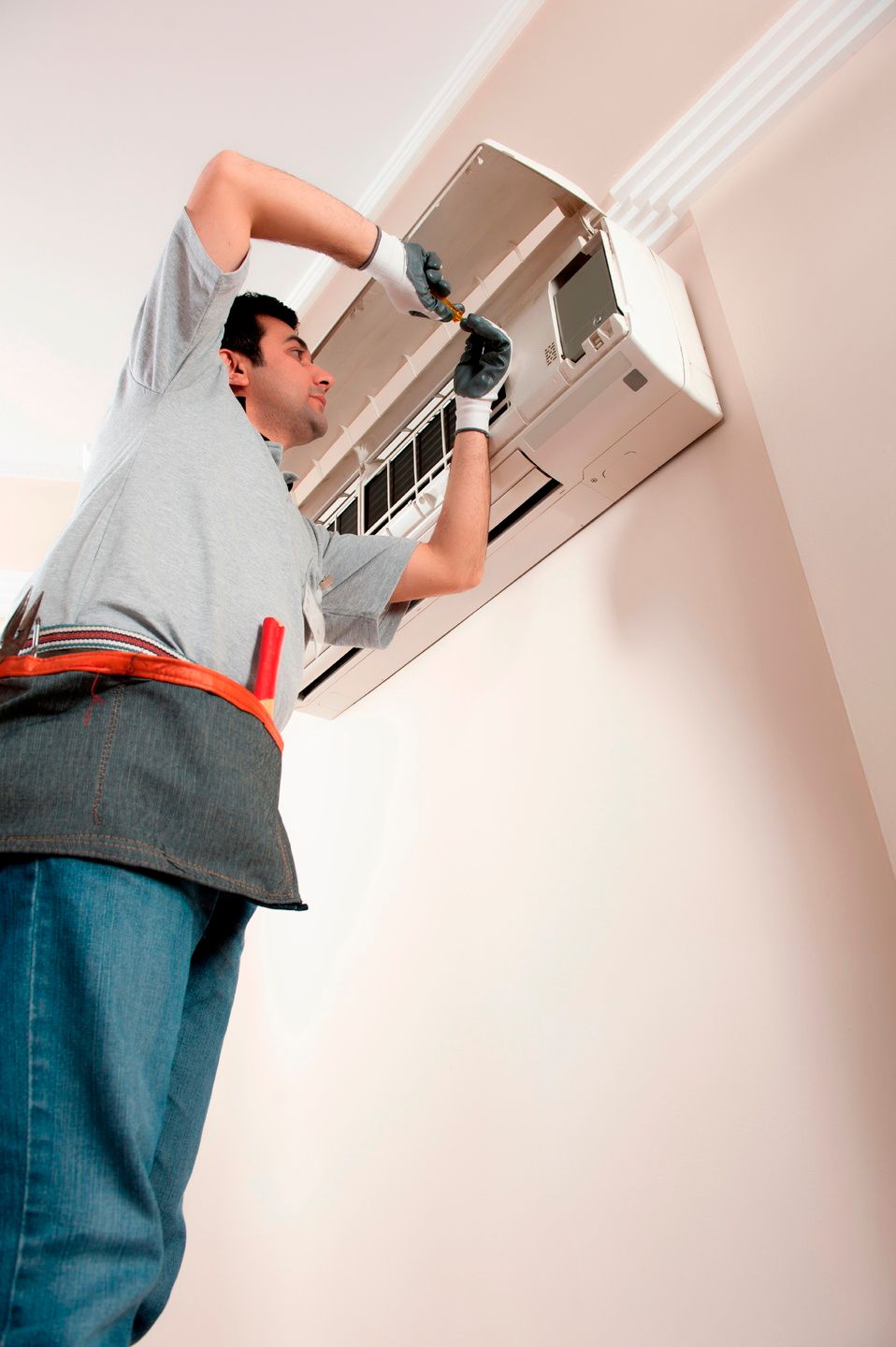 A man is working on an air conditioner on the wall.