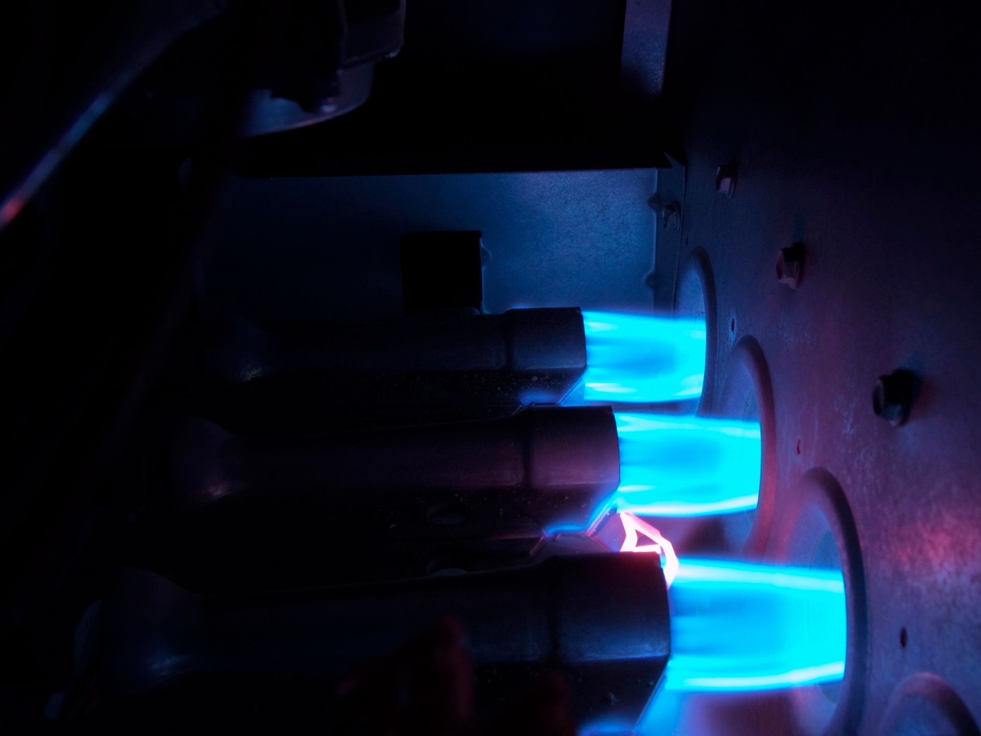 A close up of a gas burner with blue flames coming out of it.
