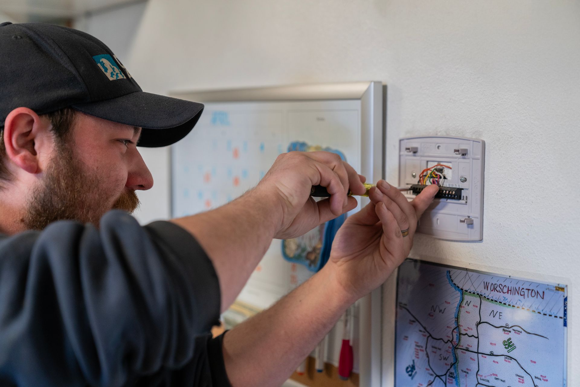 The Clean Air Act Technician is fixing a light switch on a wall.