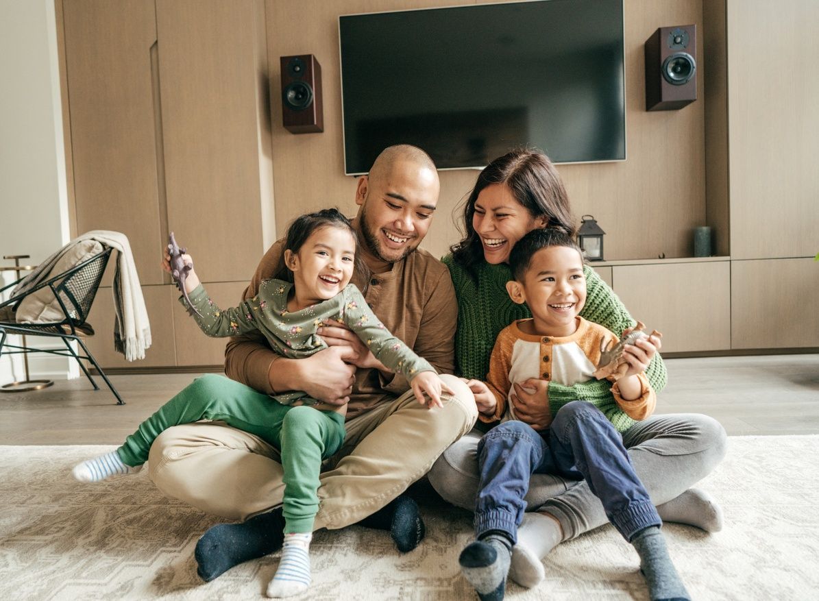 A family is sitting on the floor in a living room.