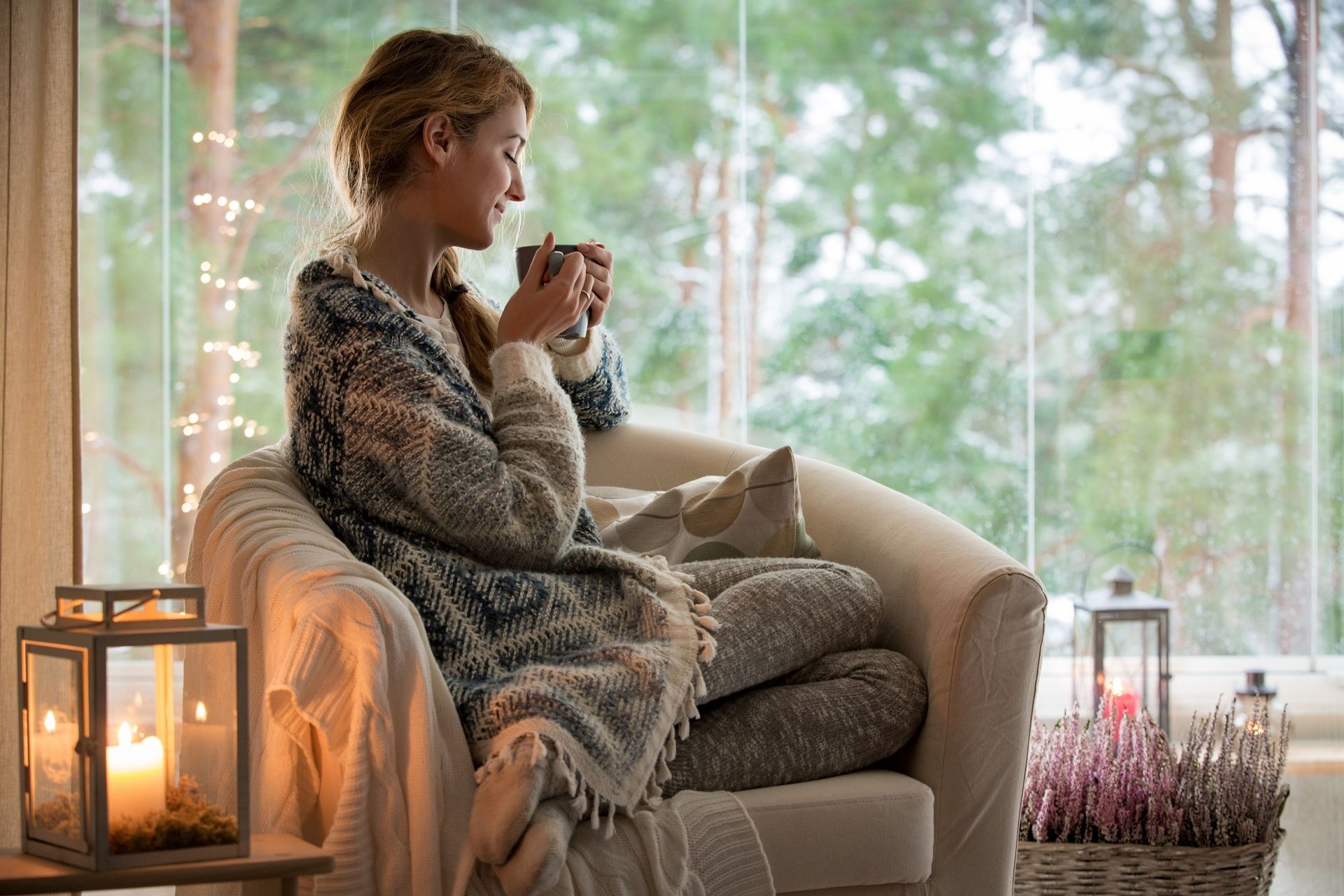 A woman is sitting on a couch drinking a cup of coffee.