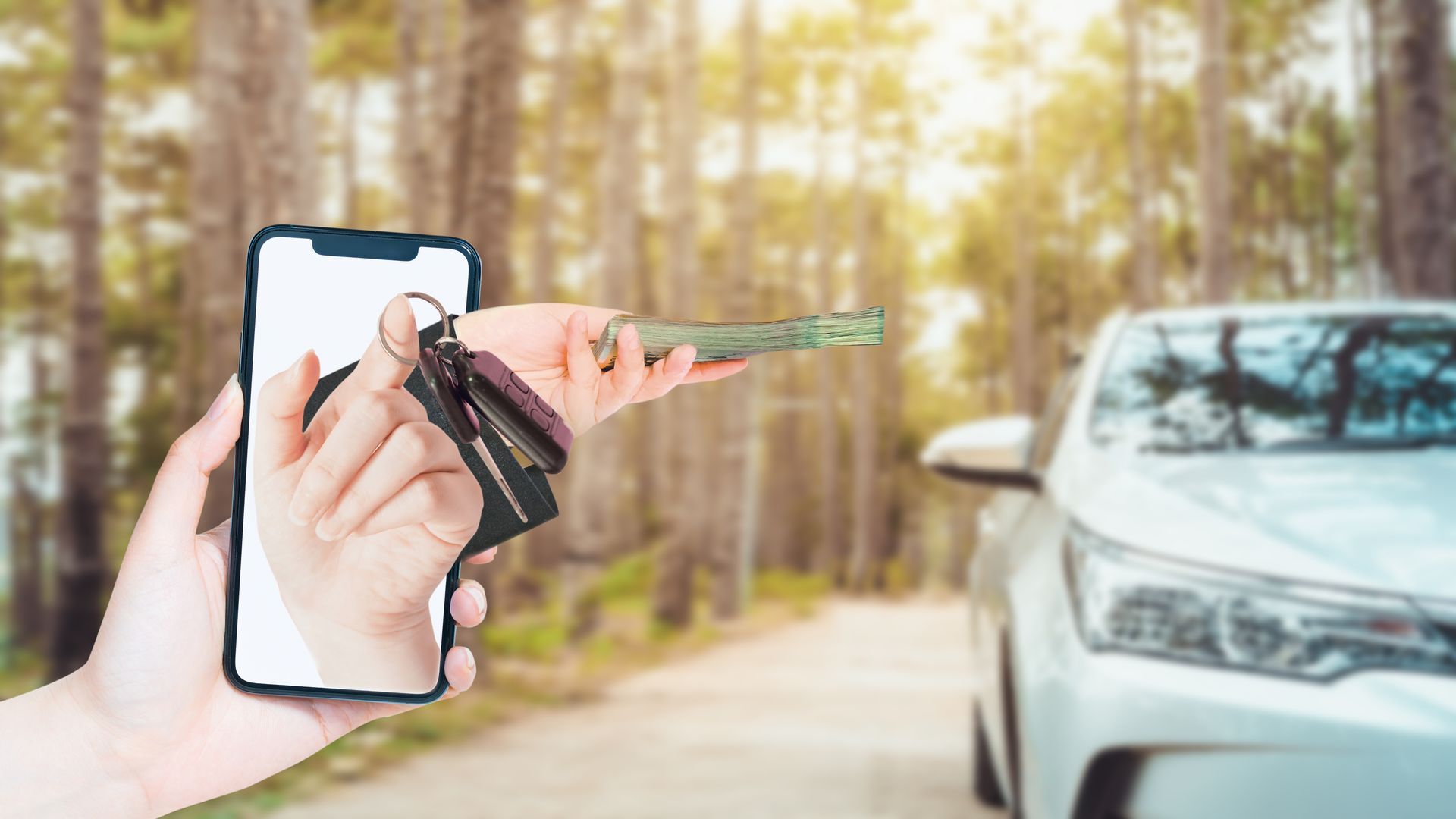 A person is holding a car key in front of a cell phone.