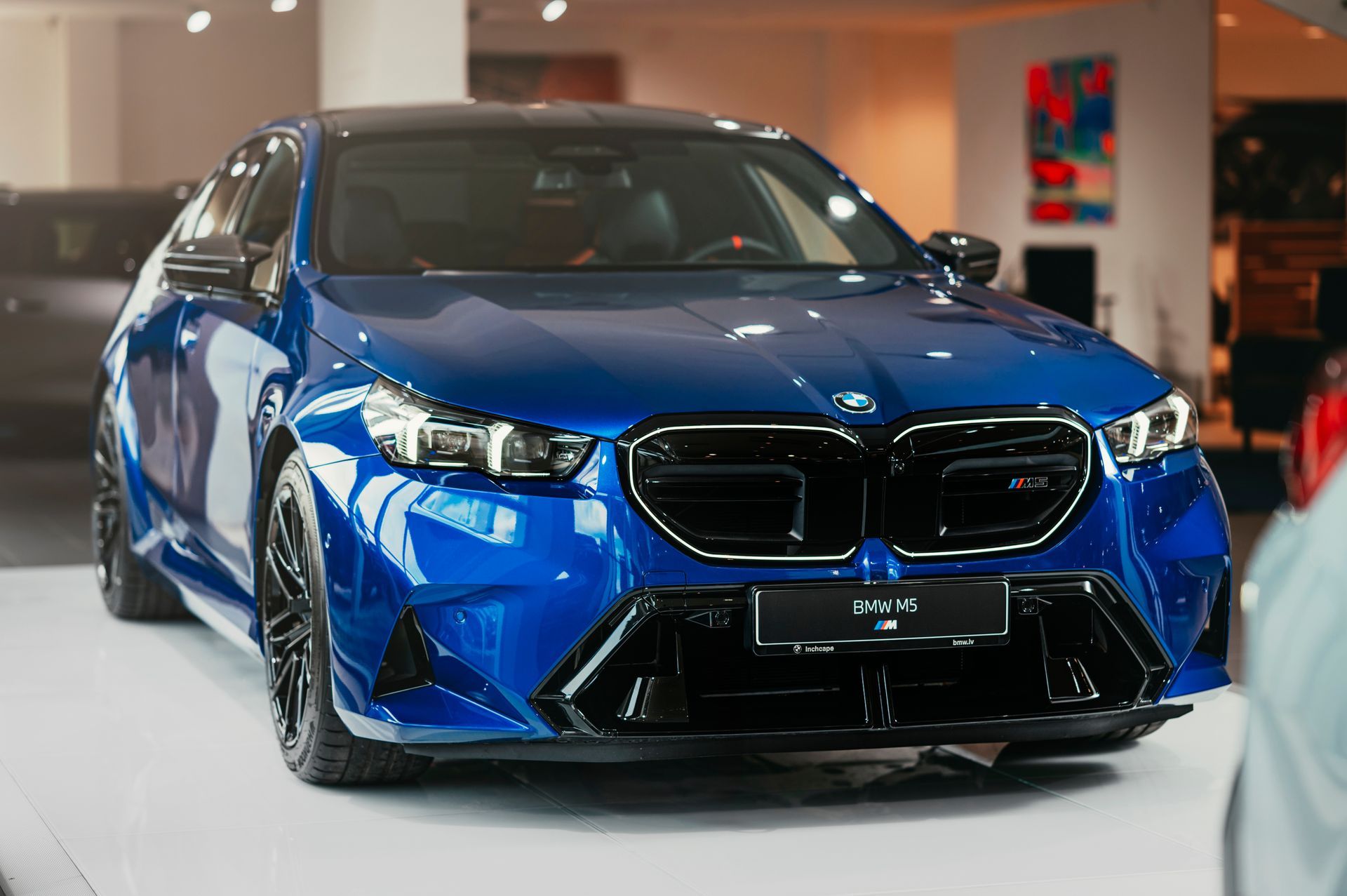 A blue bmw m5 is on display in a showroom.