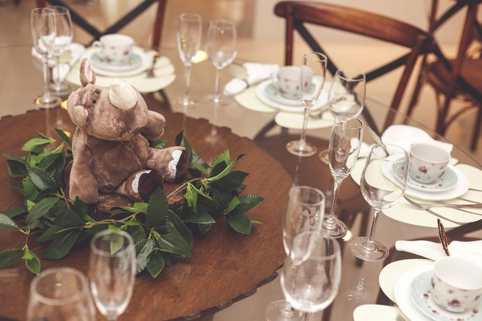 Table setting with plush animal centerpiece, glassware, and china.