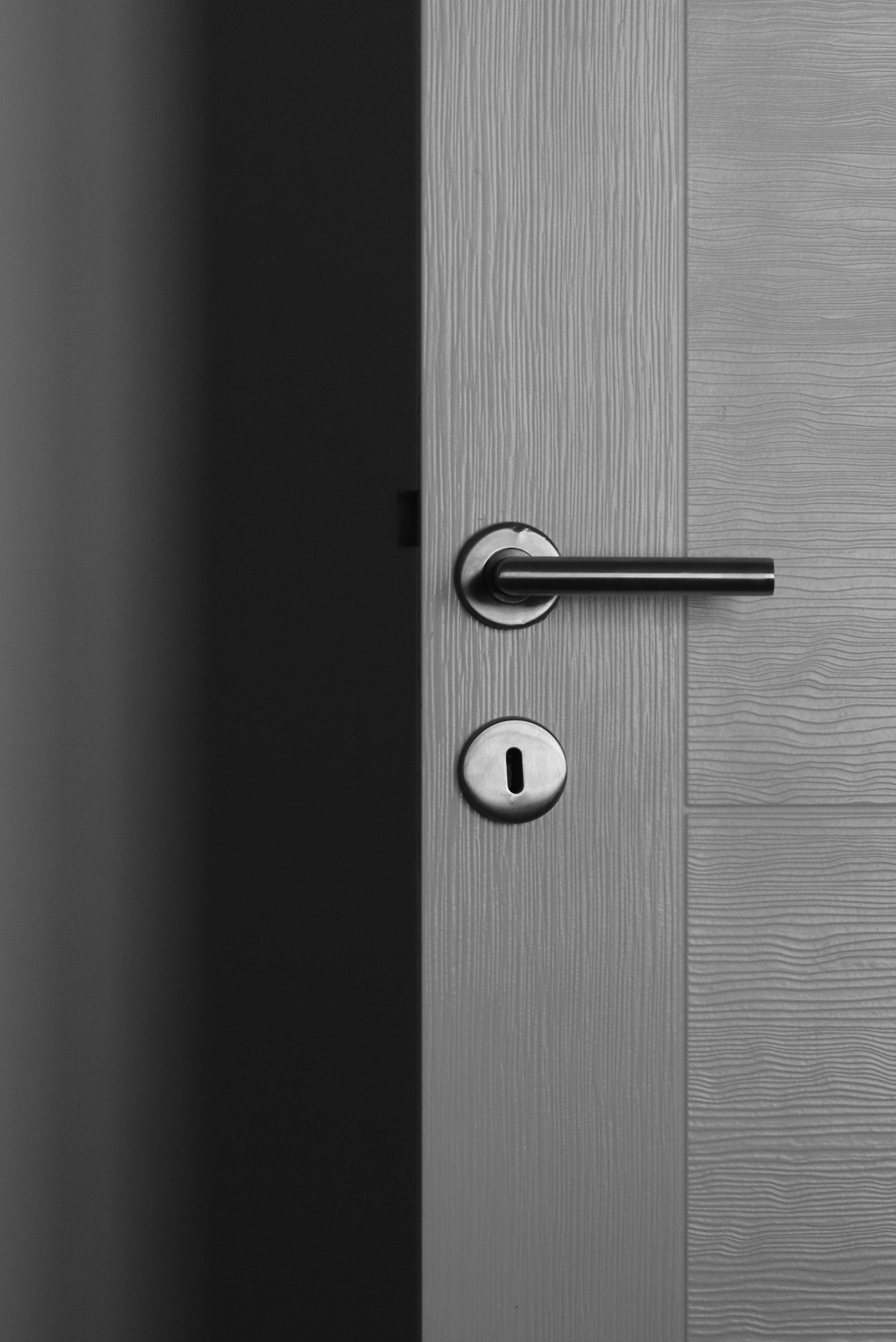 A black and white photo of a door handle and keyhole.