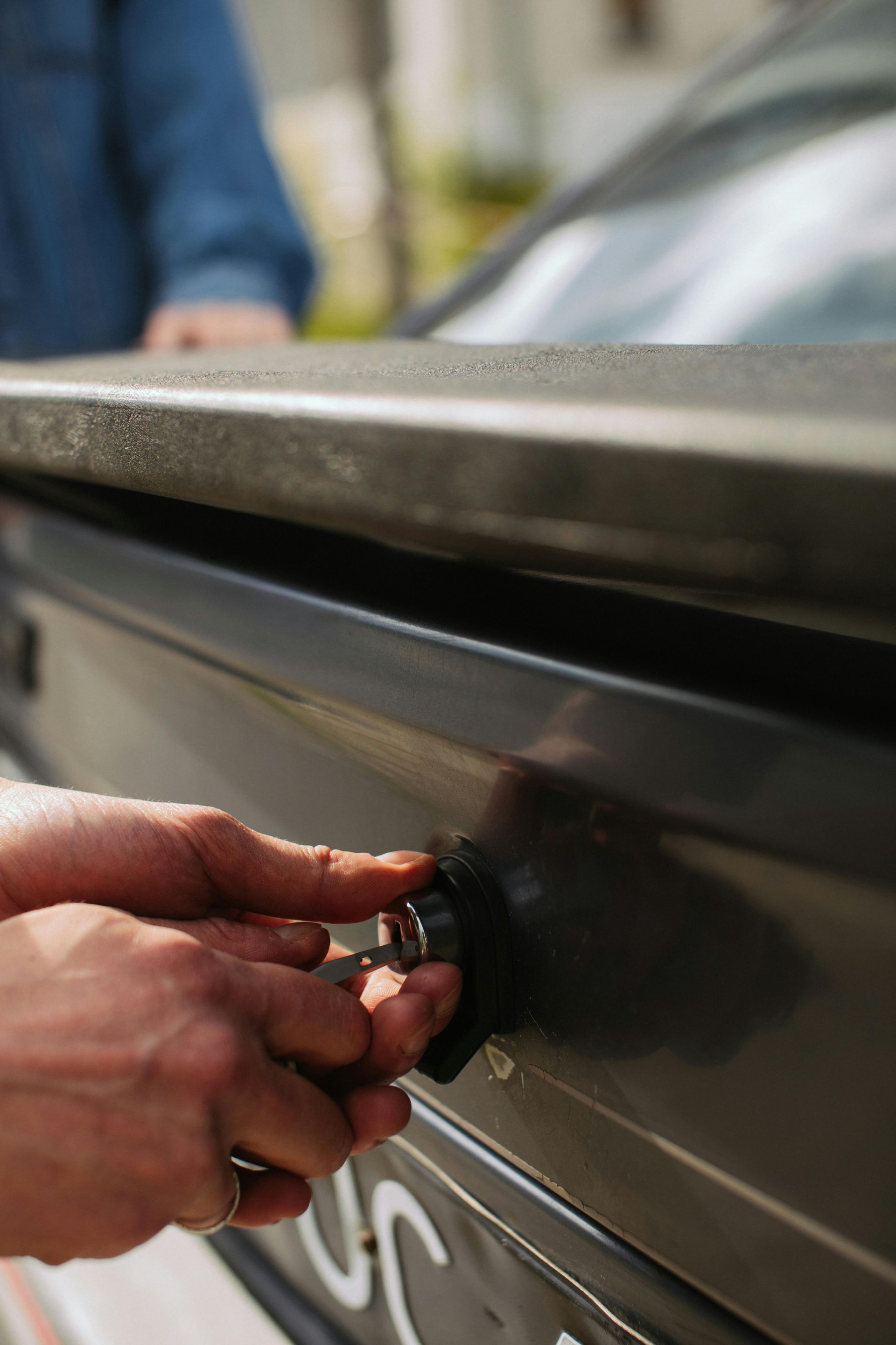 A person is opening the trunk of a car with a key.