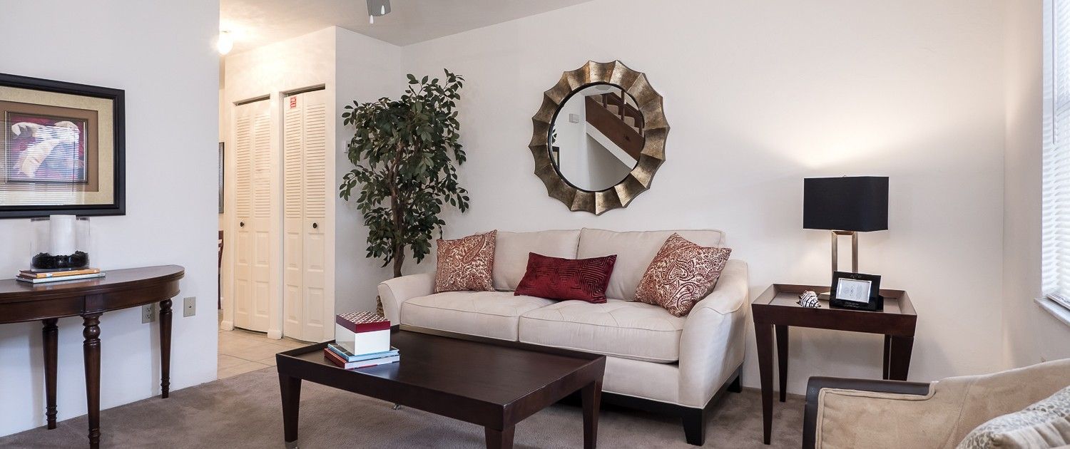 Photo of a living room with hallway in the background that has closet doors