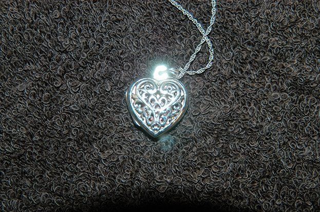 A silver necklace with a heart shaped pendant on a chain