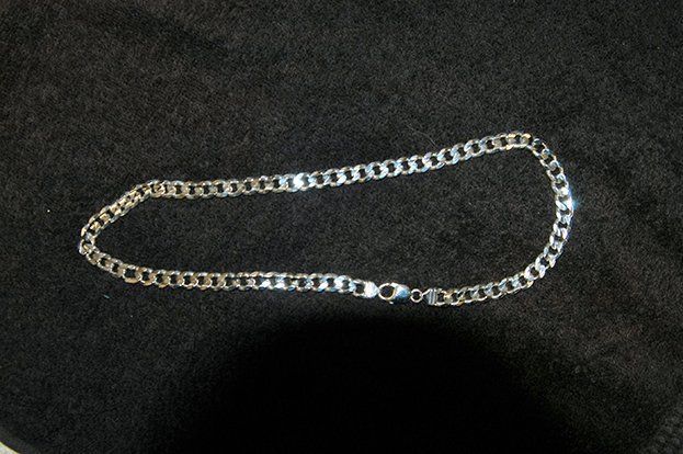 A silver chain is laying on a black cloth