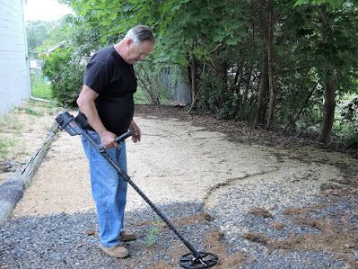 A man is using a metal detector to find something in the dirt.