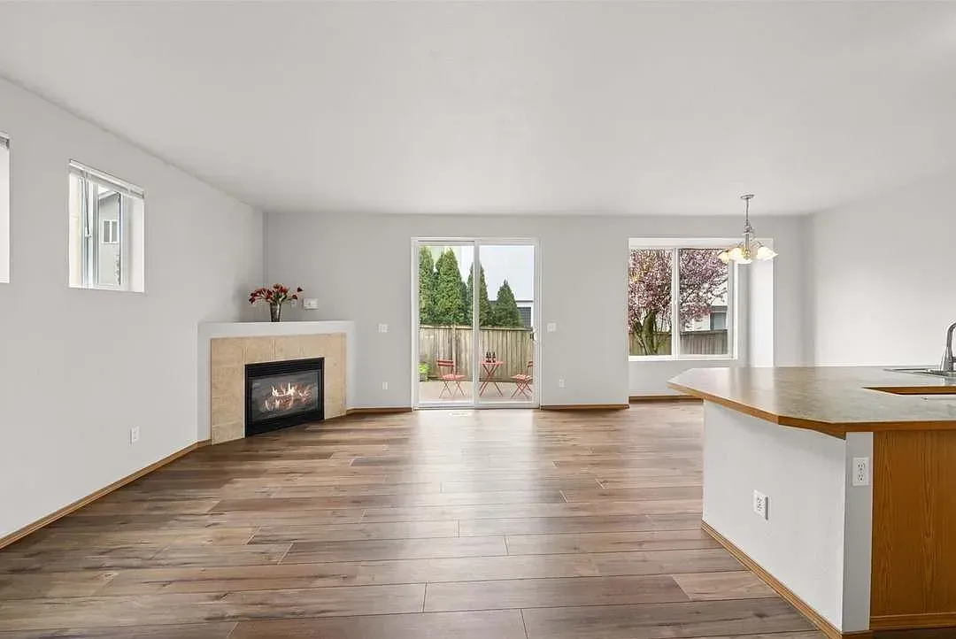 Living room with fireplace, sliding glass door to yard, wooden floor, and kitchen island.