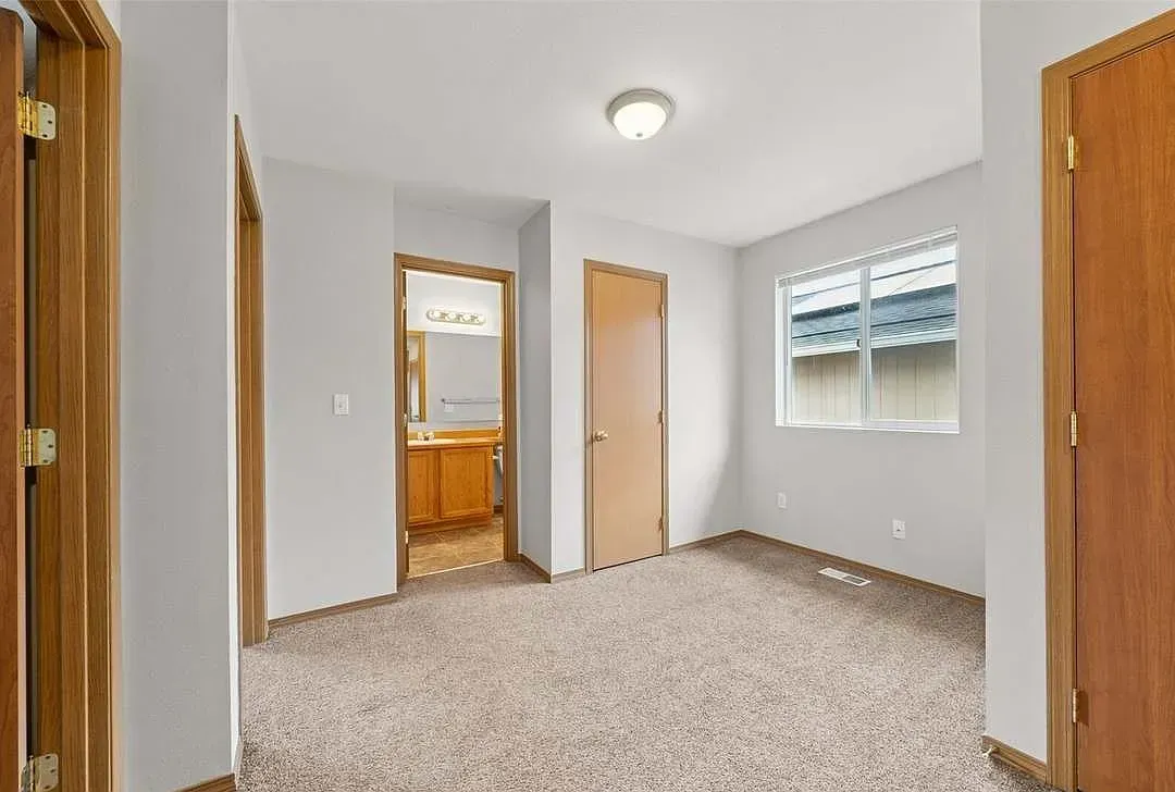 Empty bedroom with carpet, doors, and a window.