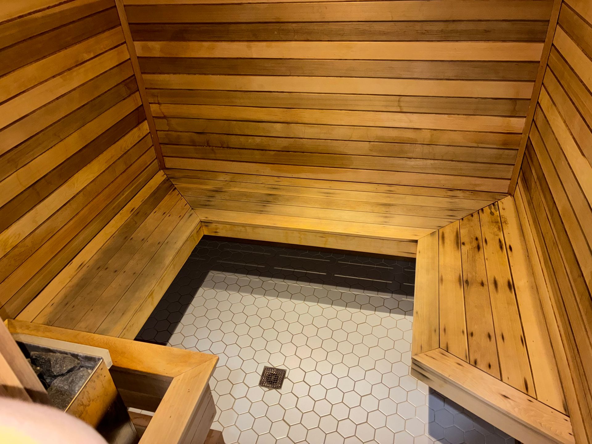 Wooden sauna interior with pebble-tile floor and bench.