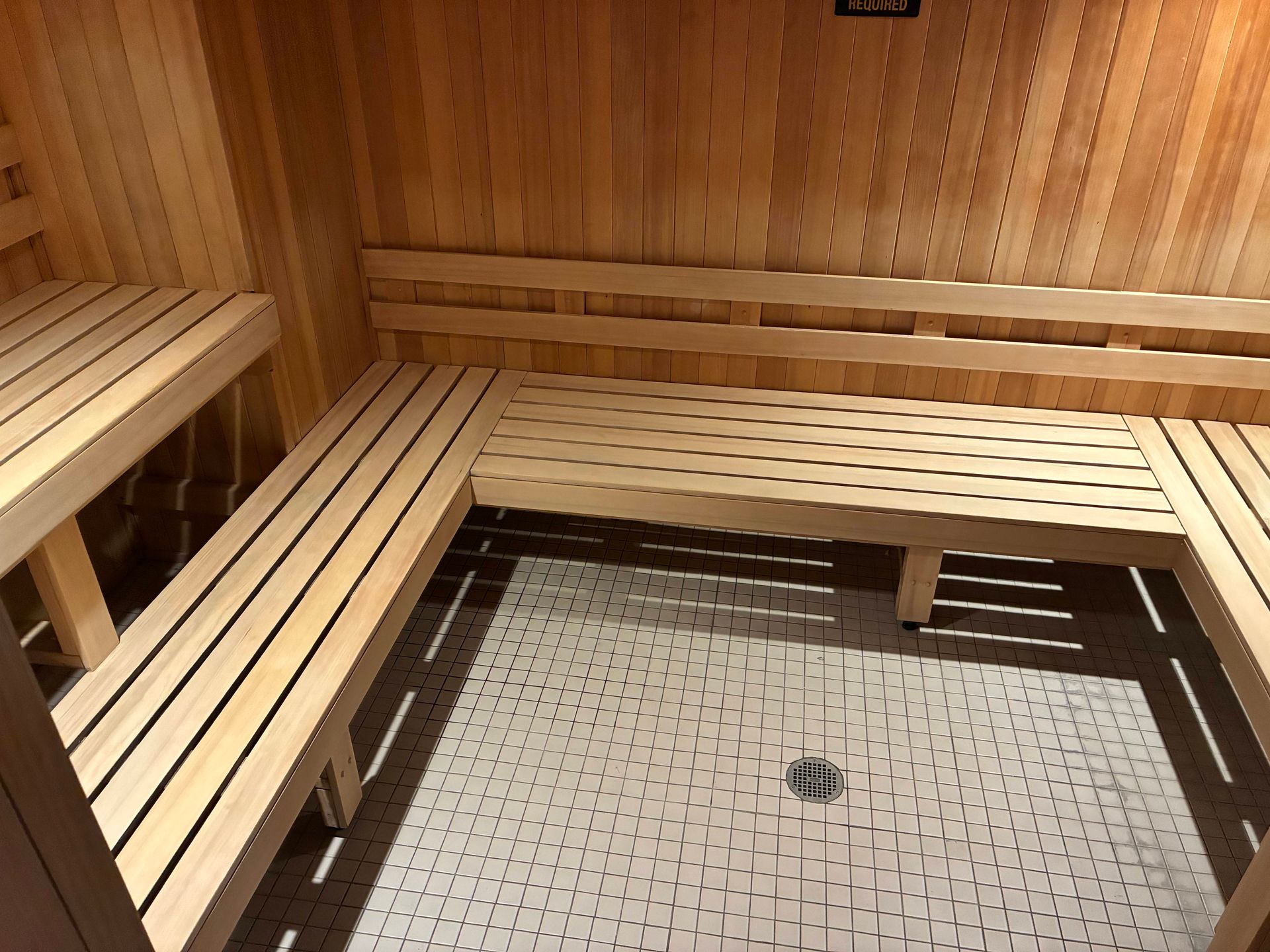Interior view of a wooden sauna with benches and tiled floor.