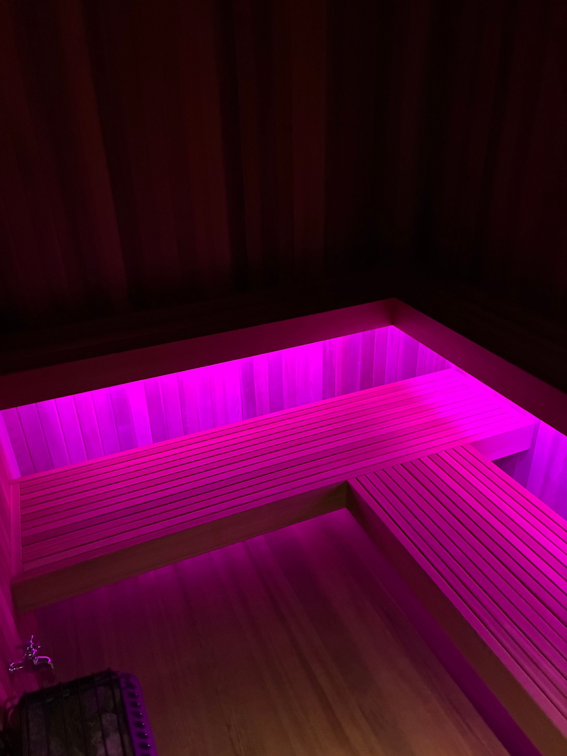 Interior of a sauna with pink LED lighting under the benches.