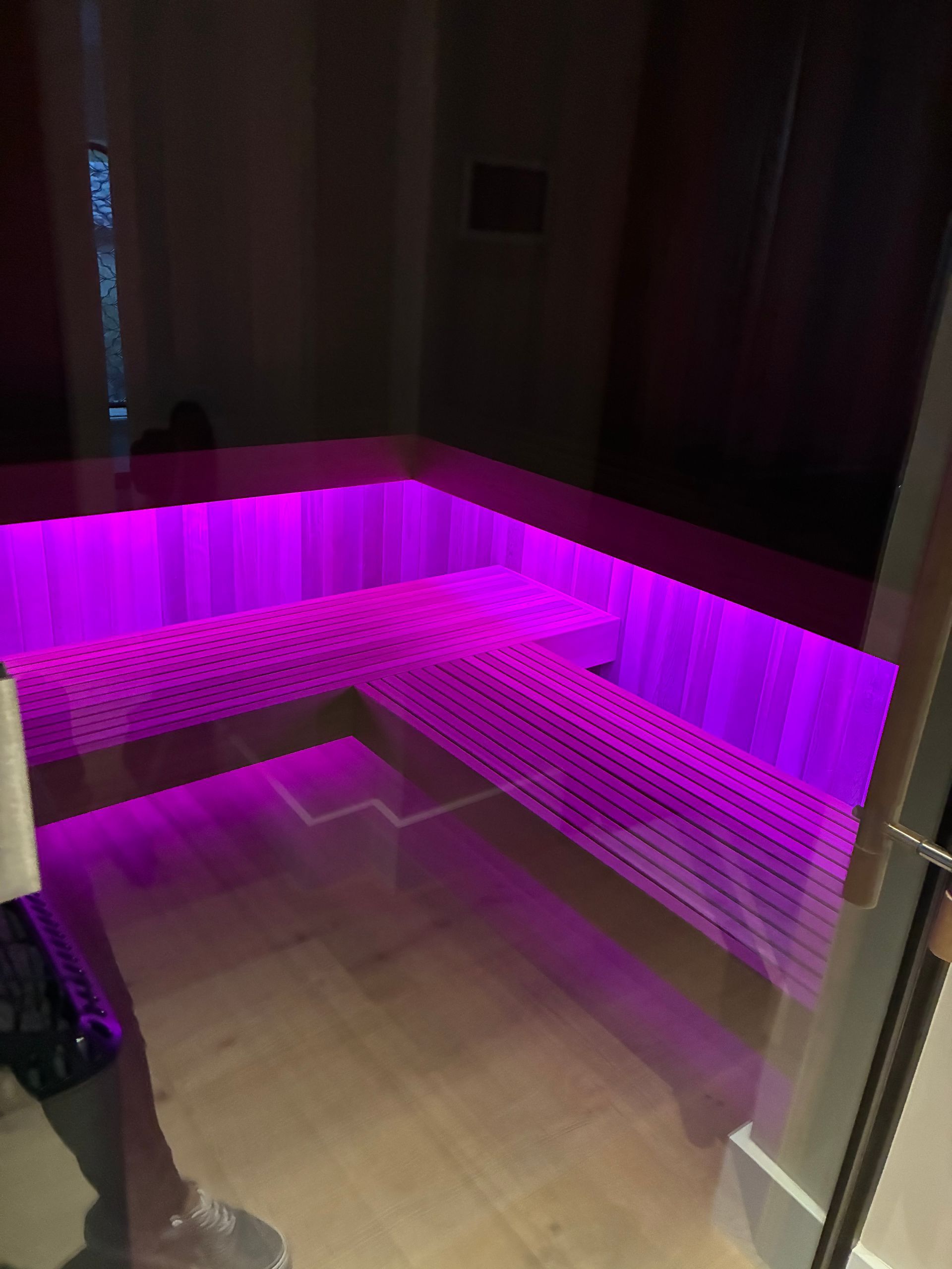 Purple-lit, built-in seating area with wooden trim, possibly a spa or relaxation space.
