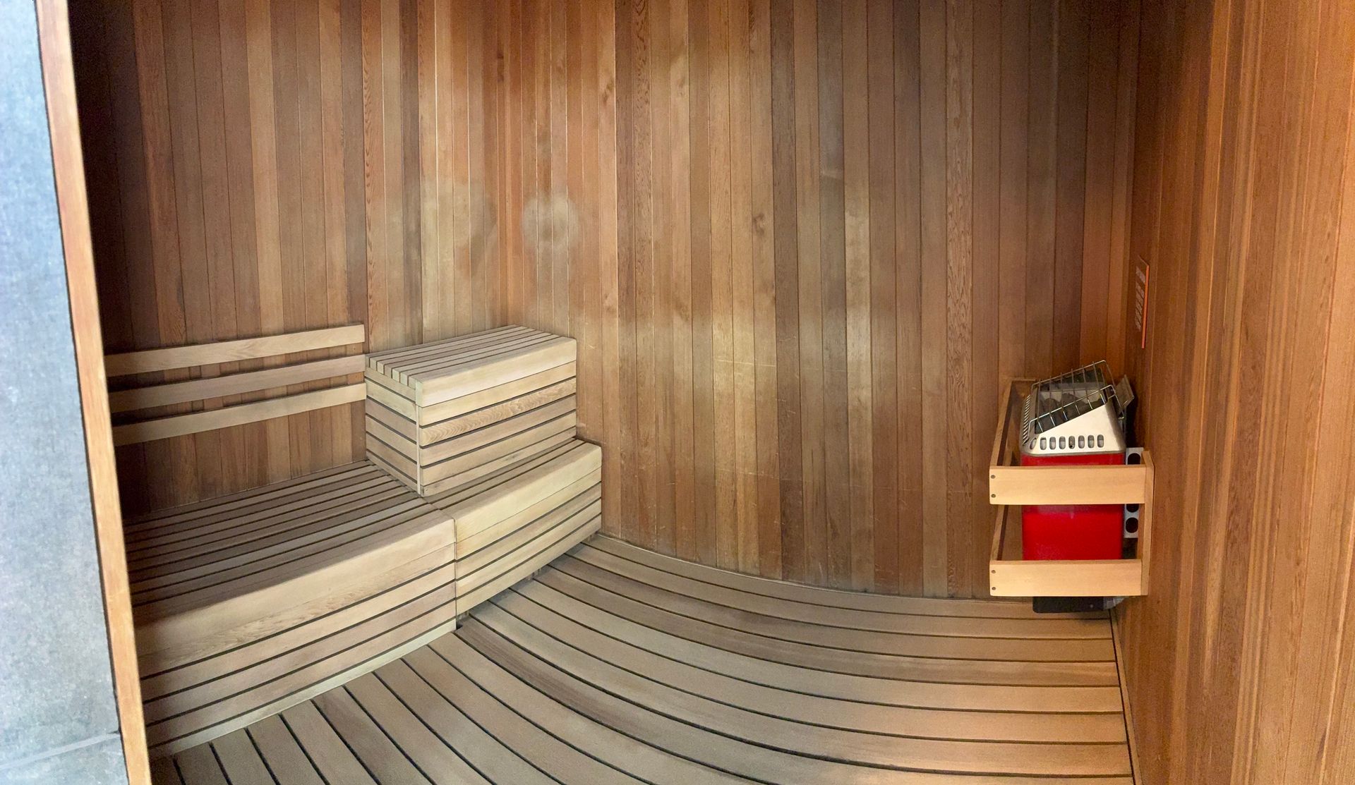 Wooden sauna interior with benches, heater, and wood paneling.