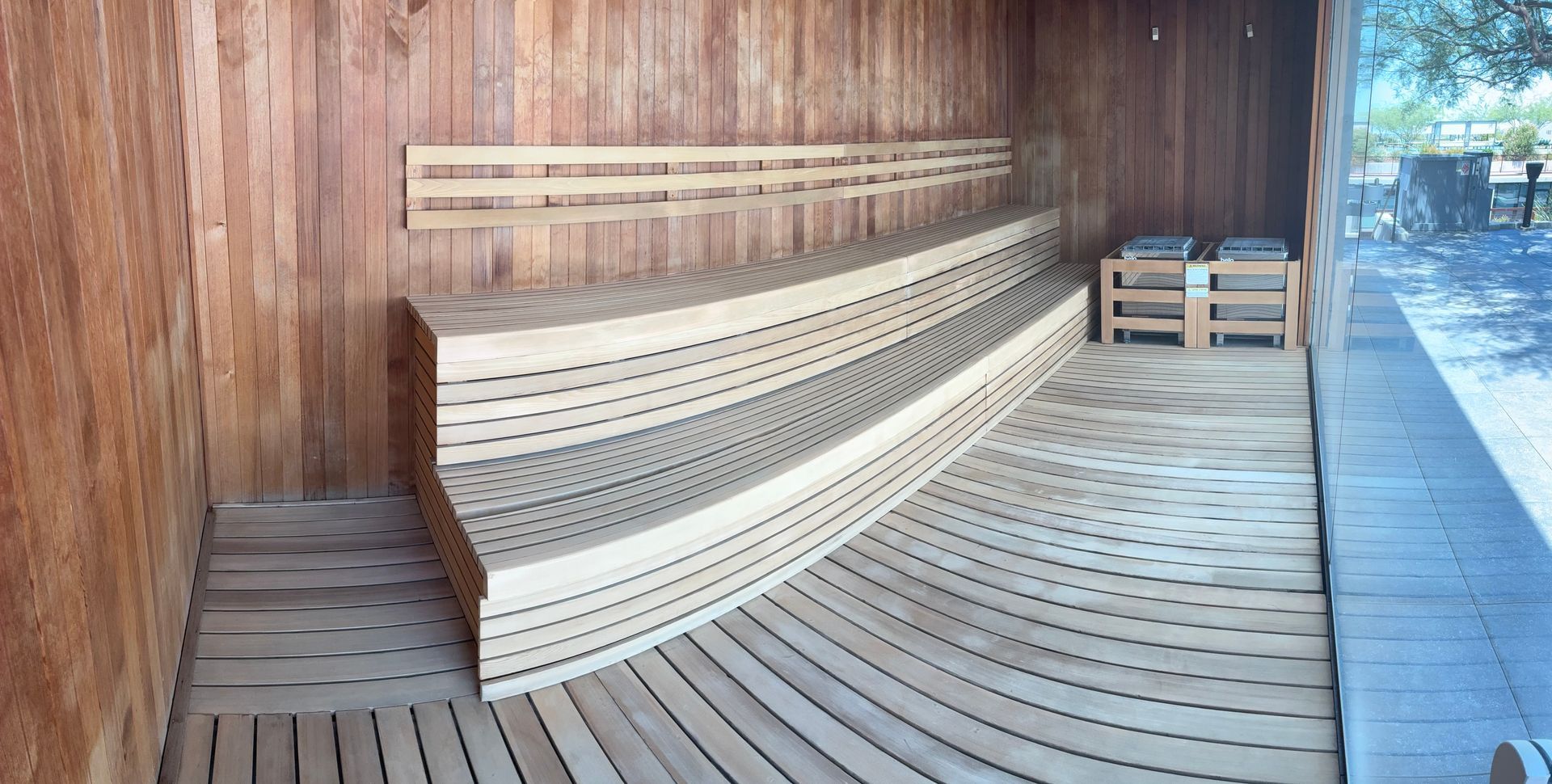 Wooden sauna interior with curved benches and heating unit.