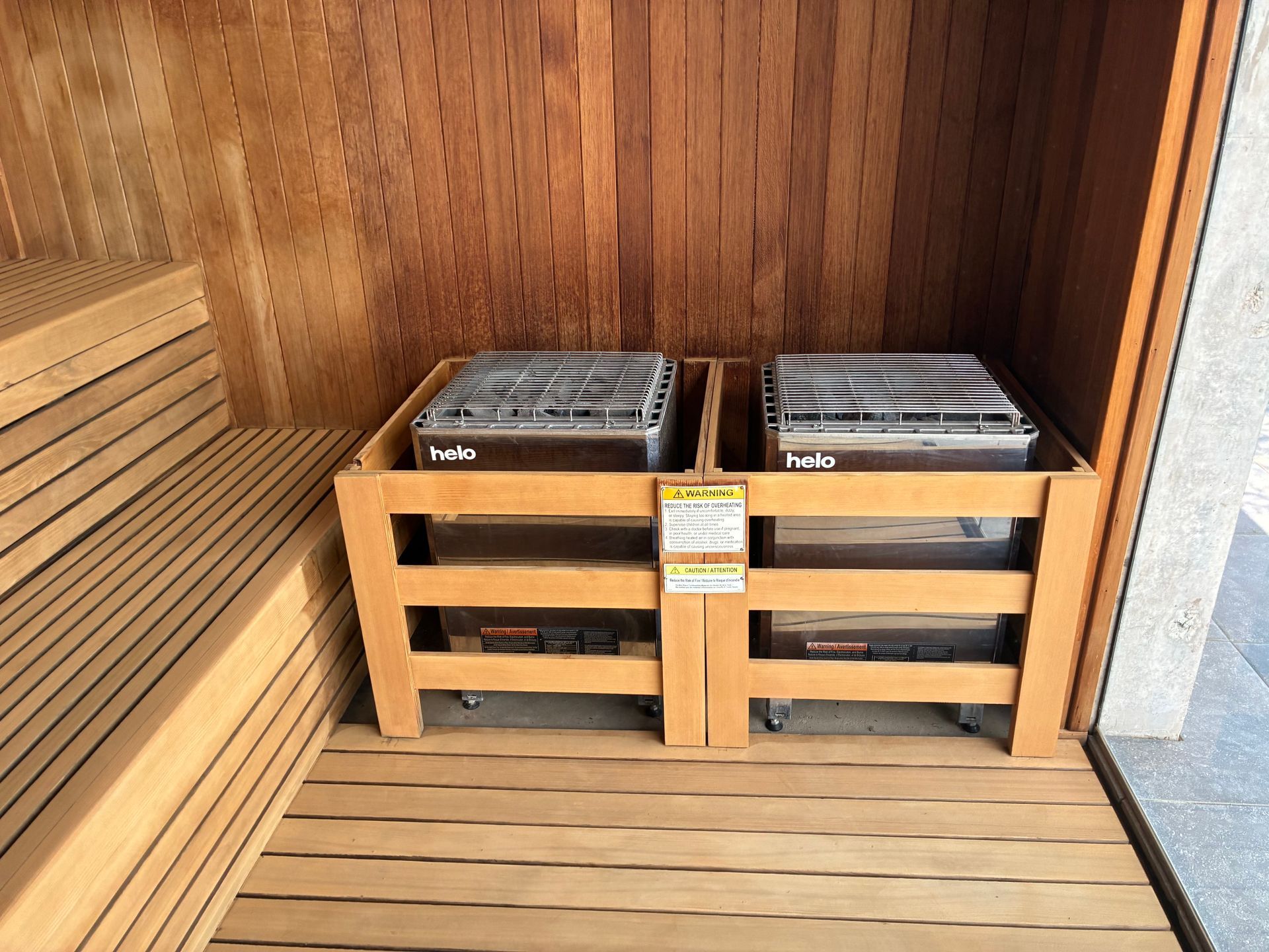 Wooden sauna interior with two heaters in a wooden enclosure.