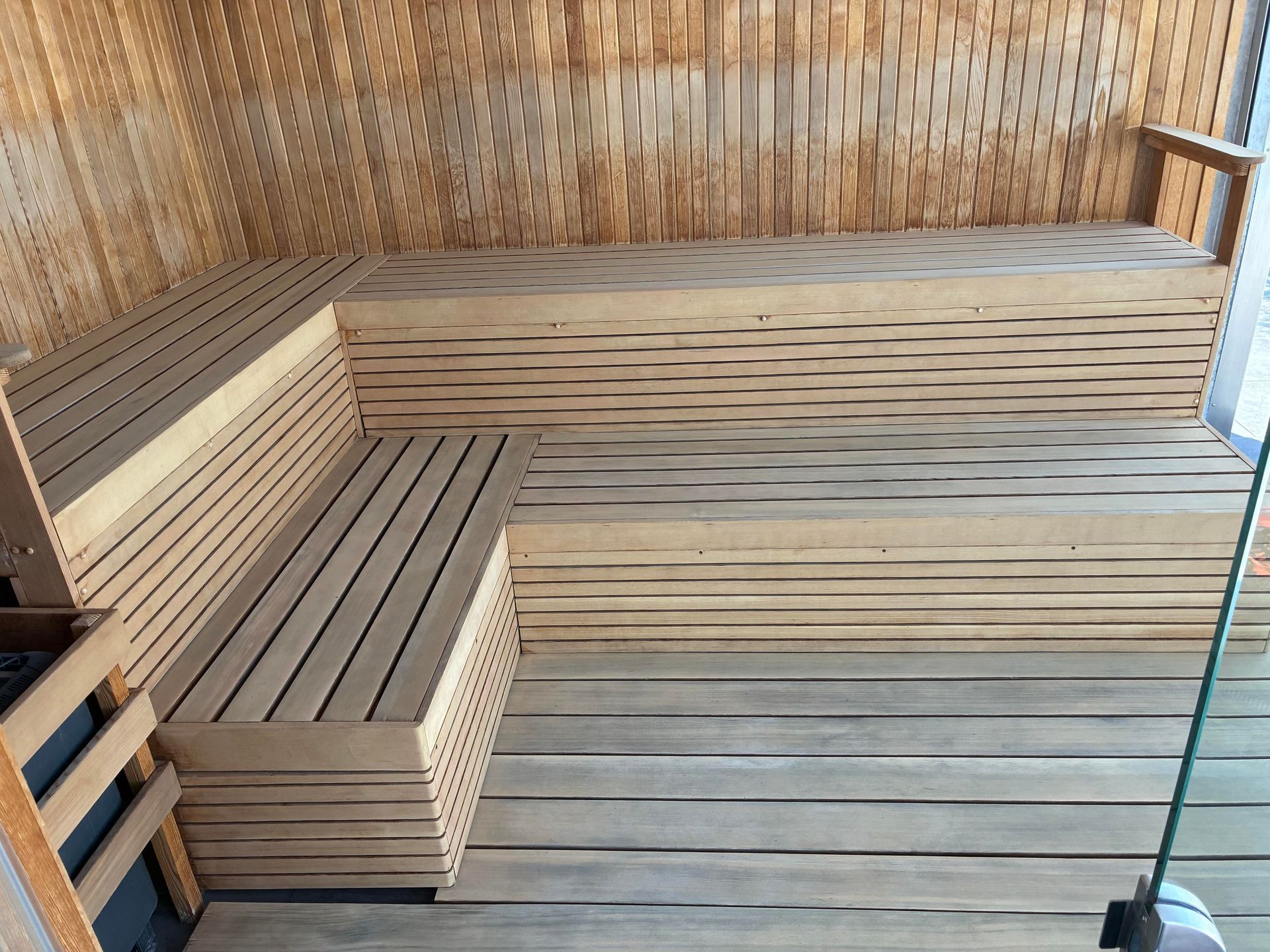 Wooden sauna interior with tiered benches and light wood paneling.