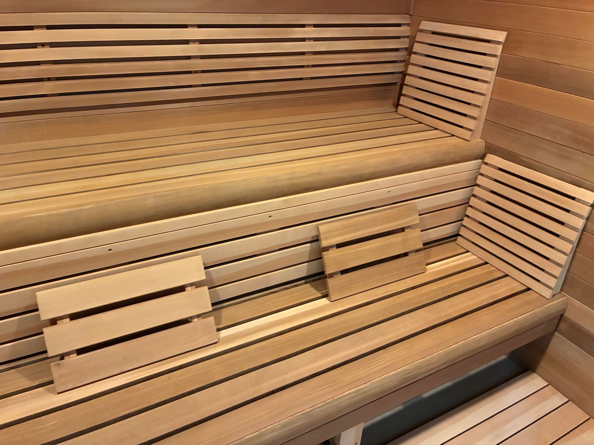 Wooden sauna interior with slatted benches and backrests.