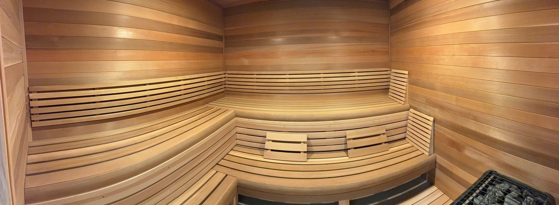 Interior of a wooden sauna with tiered benches. The walls are made of wooden planks.