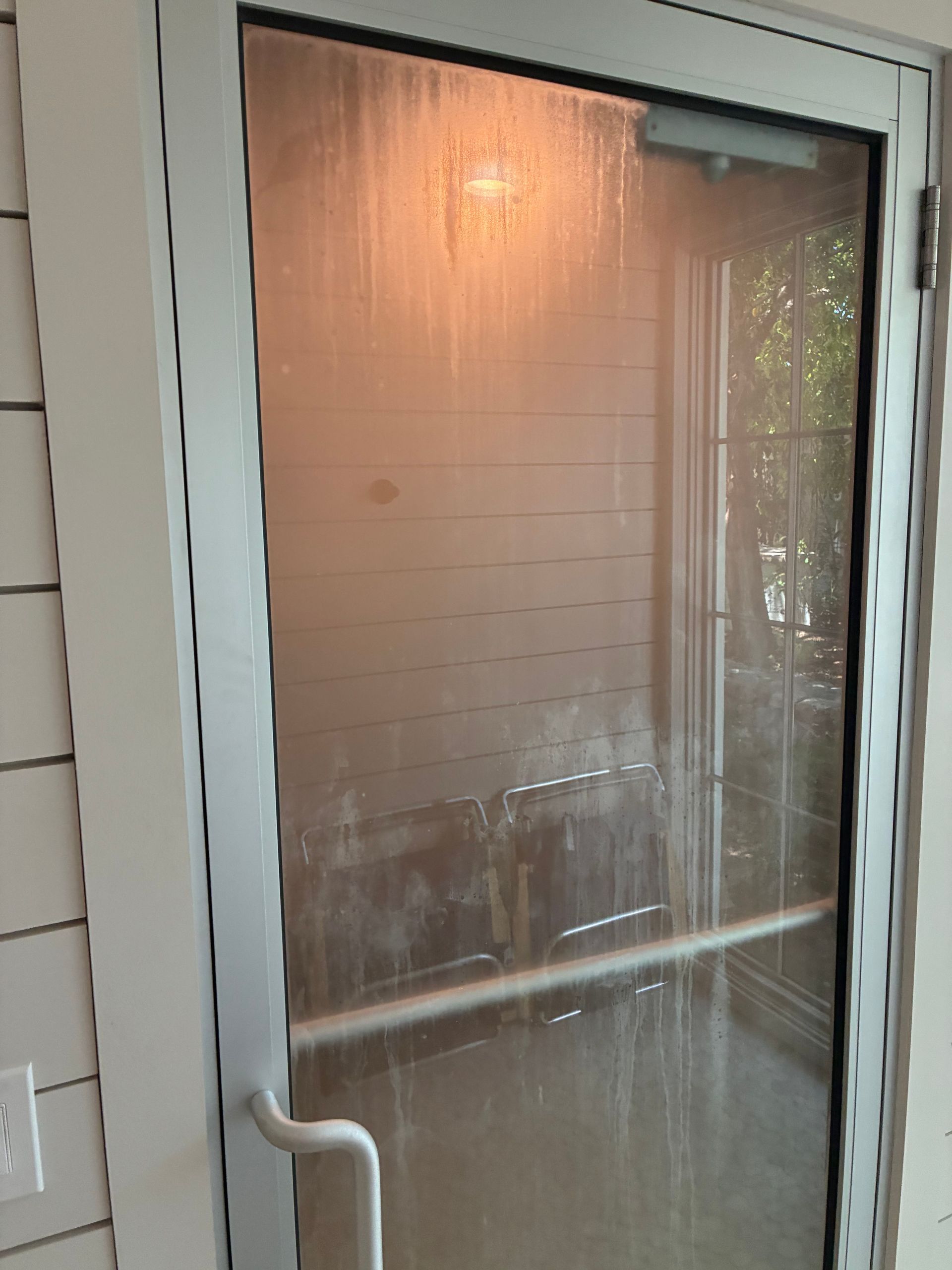 Glass door with metal frame; light shines through. Door has a handle and horizontal bar.