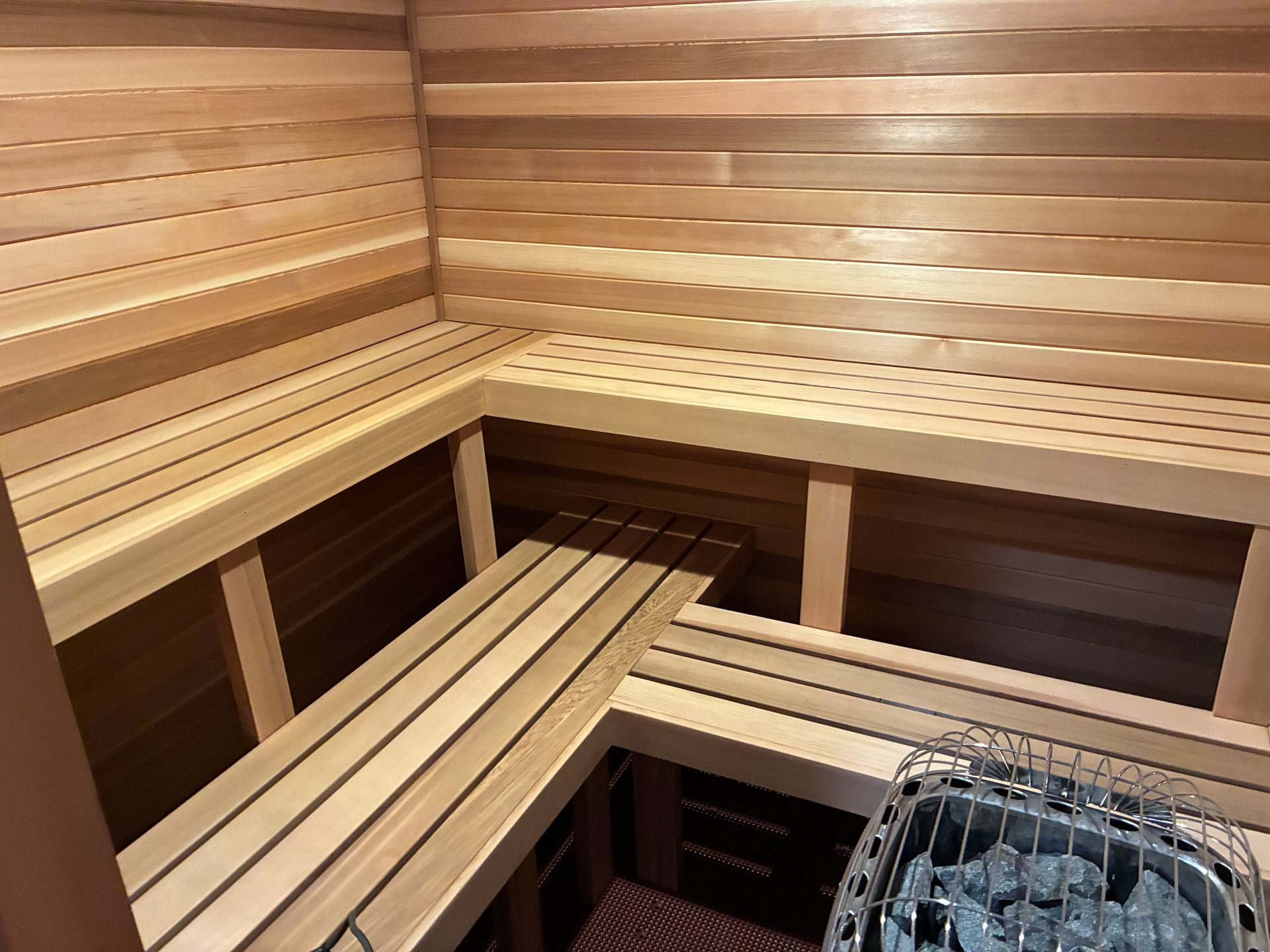 Wooden sauna interior with tiered benches and a heater.