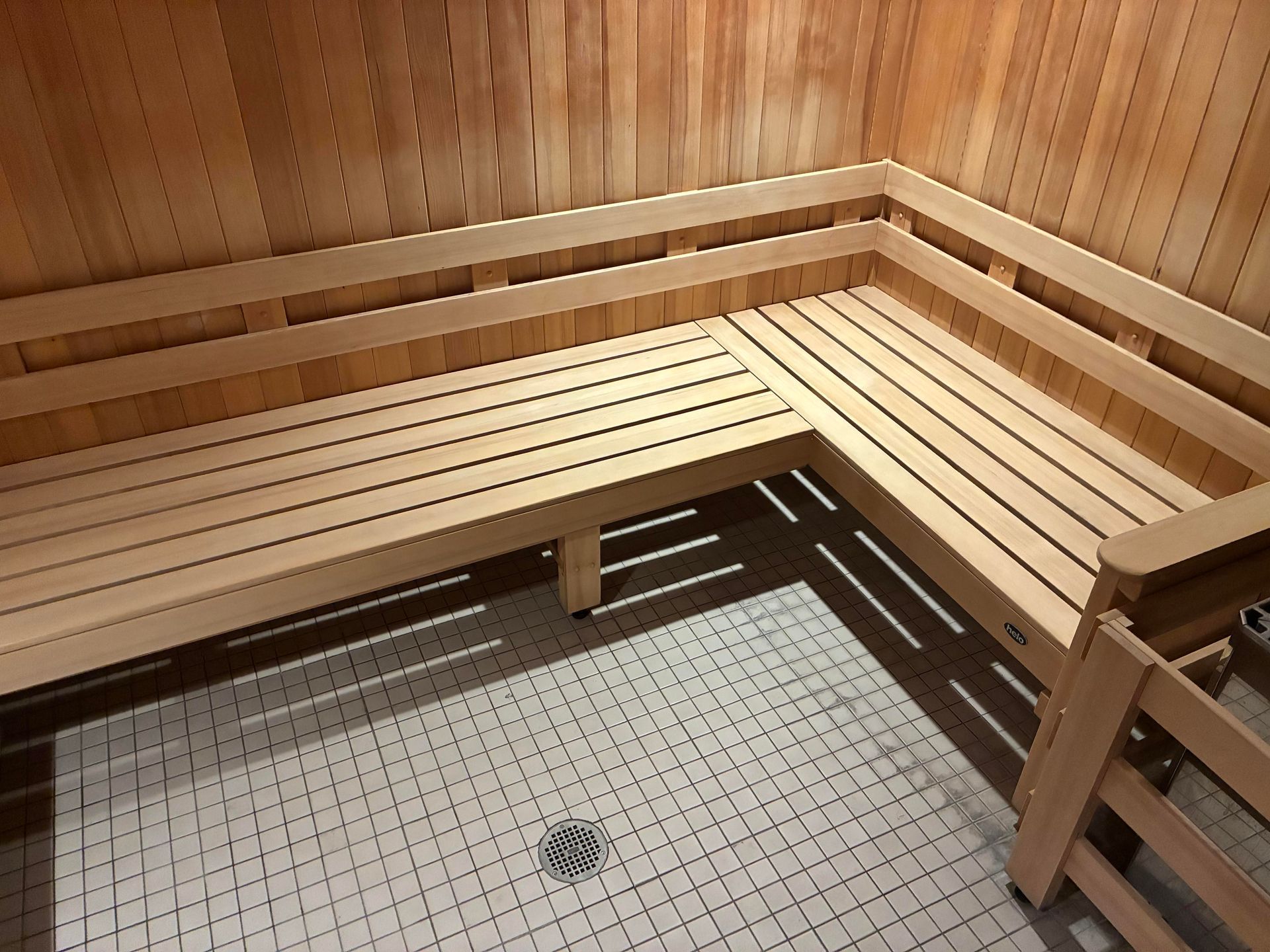 Wooden sauna interior with tiered benches, tile floor, and cedar walls.