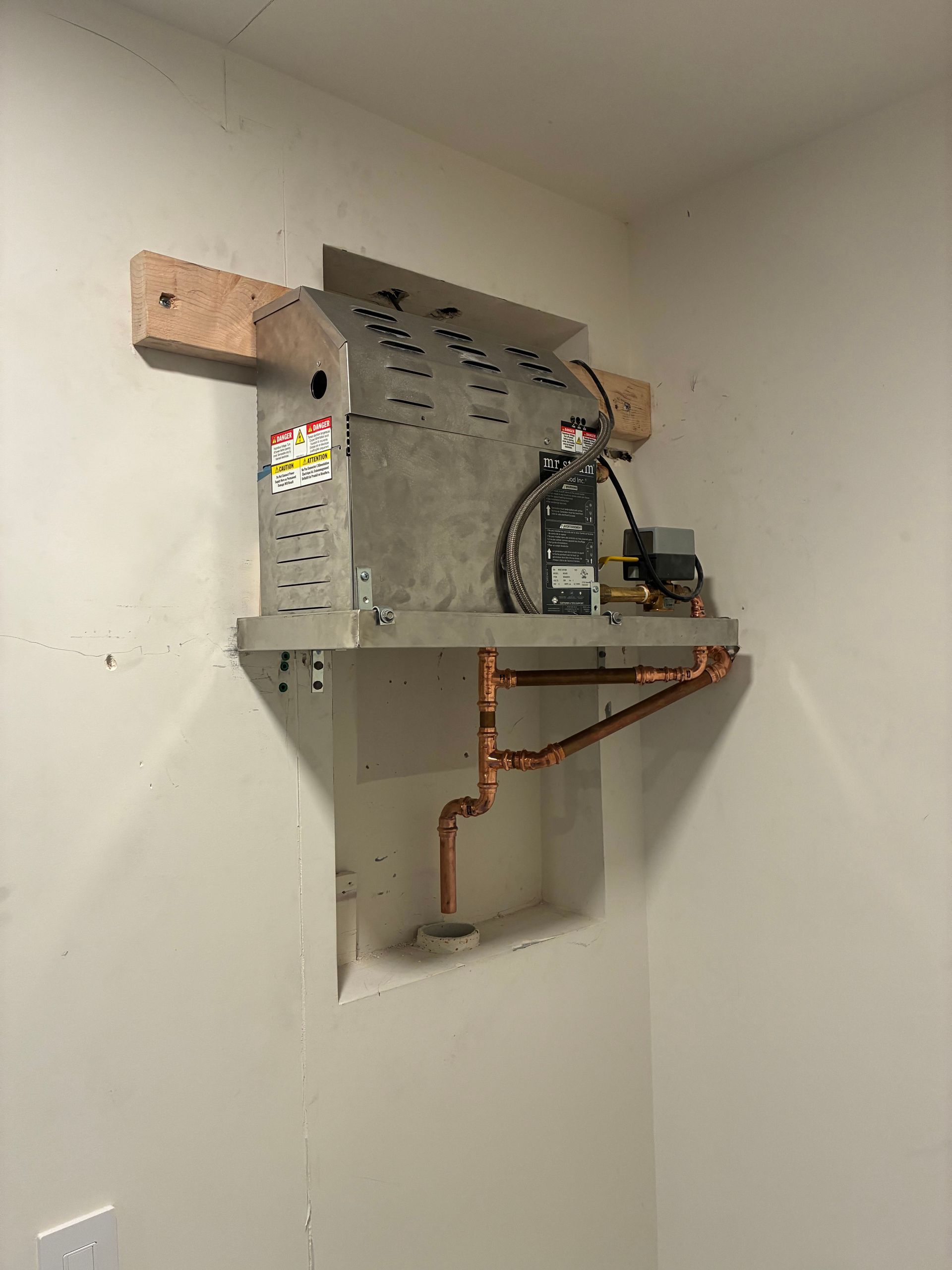 Gray and copper utility box mounted on a white wall, with copper piping below.