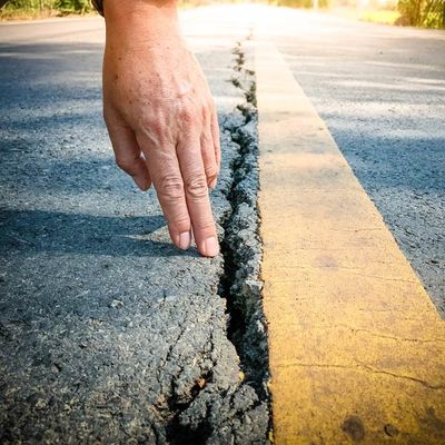 Hand Touching a Crack on Asphalt — Pikefield, NC — Asphalt Services of Goldsboro
