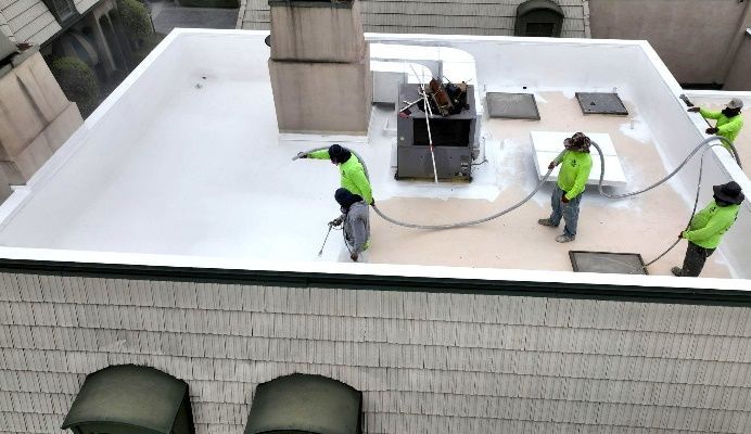 A group of workers are painting a roof.
