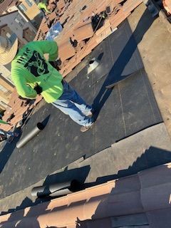A man in a green shirt is working on a roof.