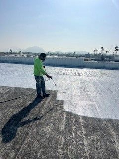 A man is spraying a roof with a sprayer.