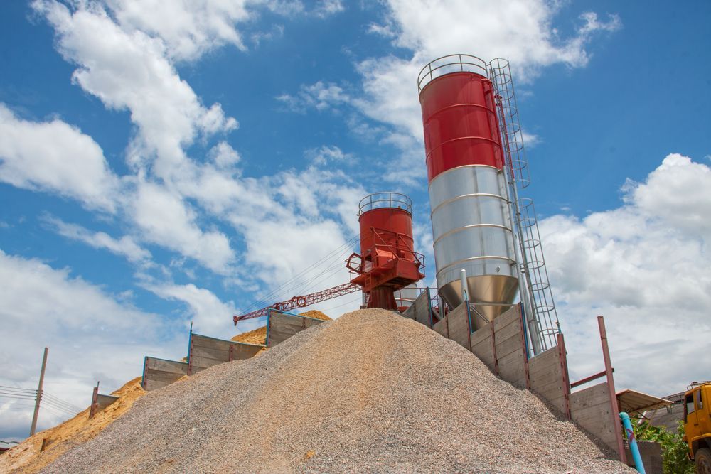 Two Silos, Red and Silver, on a Pile of Gravel Against a Blue Sky — Salisbury Concrete Contractors In Ocean Shores, NSW