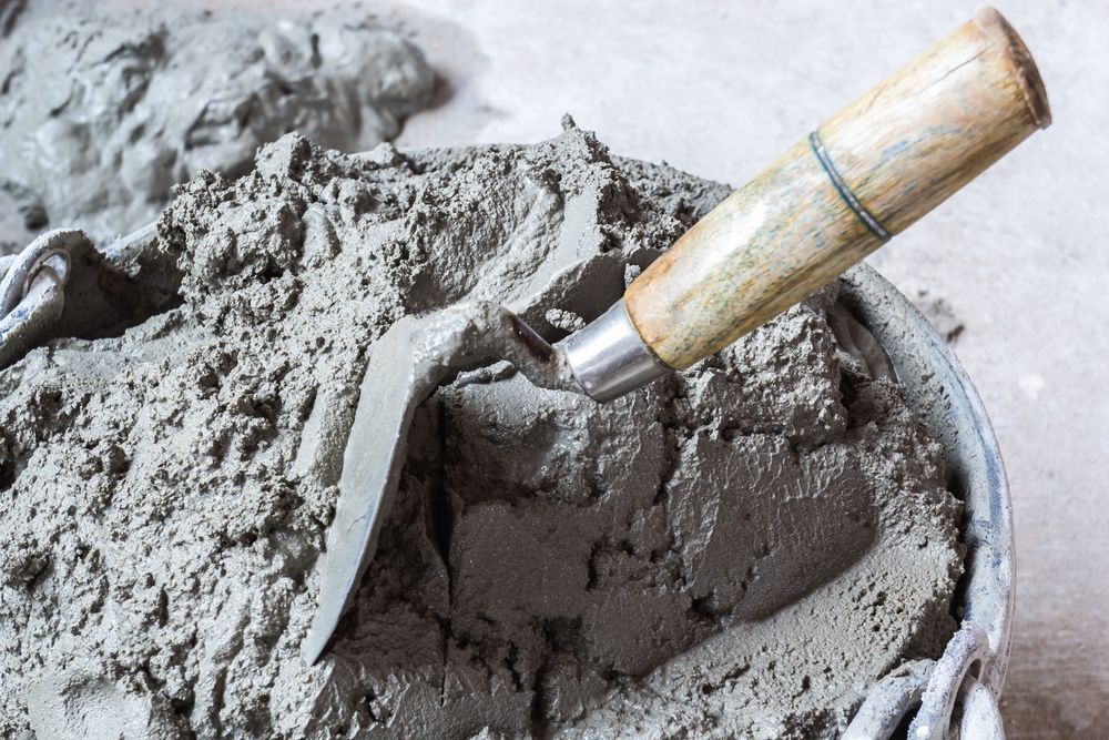 Trowel Resting in a Bucket of Wet Cement, Gray Color — Salisbury Concrete Contractors In Ocean Shores, NSW