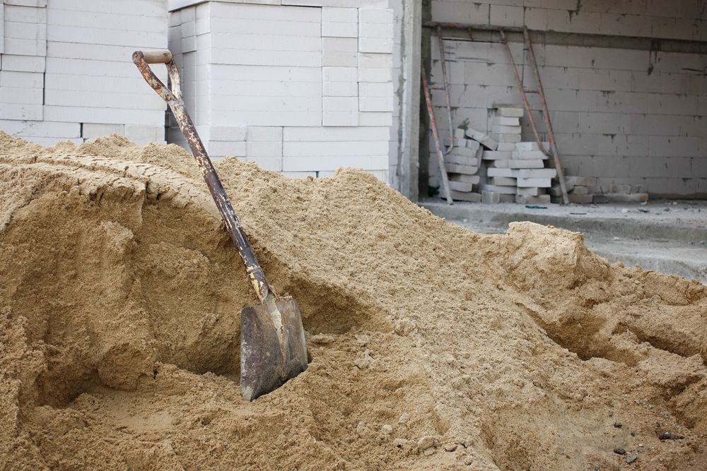 A Shovel Stuck in a Pile of Sand at a Construction Site — Salisbury Concrete Contractors In Ocean Shores, NSW