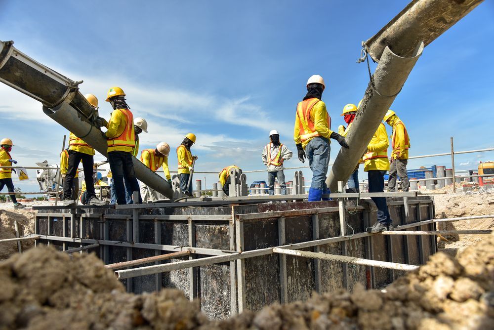 Construction Workers Pouring Concrete Into a Wooden Form— Salisbury Concrete Contractors In Lennox Head, NSW