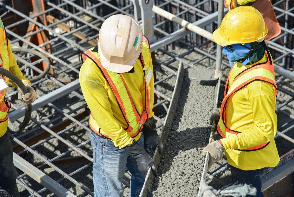 Construction Workers Pouring Concrete, Wearing Yellow Safety Vests — Salisbury Concrete Contractors In Ocean Shores, NSW