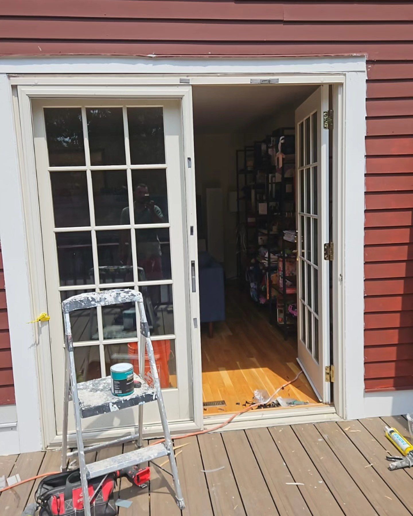 Sliding glass door and French door open to a room with bookshelves, construction tools and a stepladder outside.