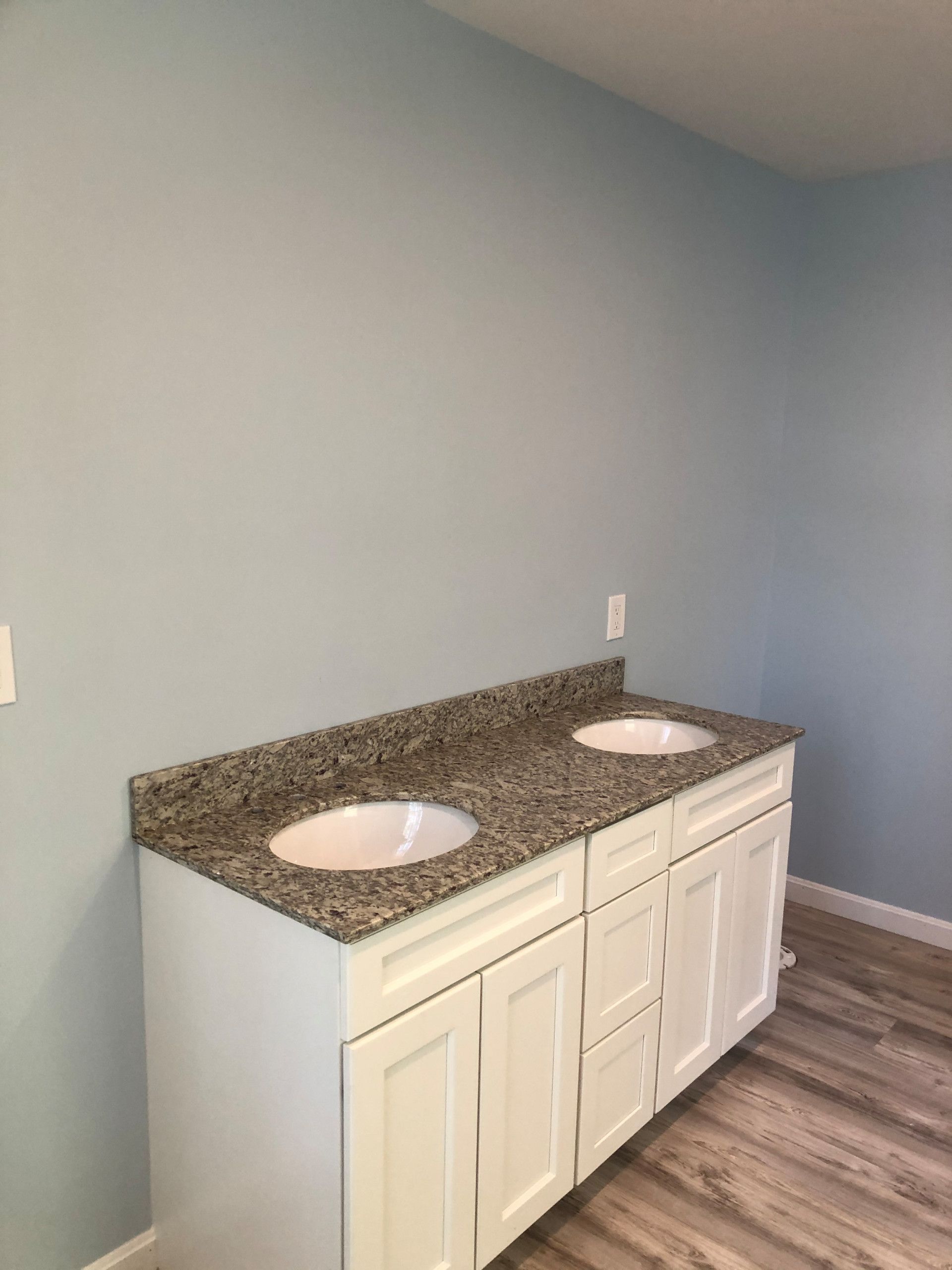 White double sink vanity with granite countertop in a blue-walled bathroom.