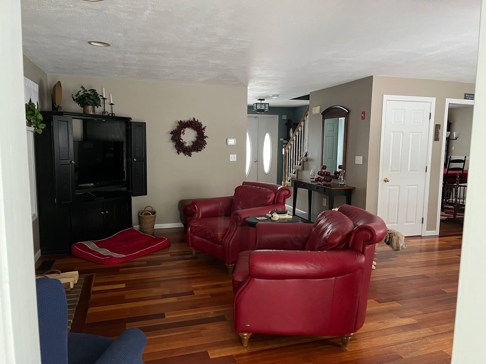 Living room with red leather chairs, black entertainment center, and wooden floor.