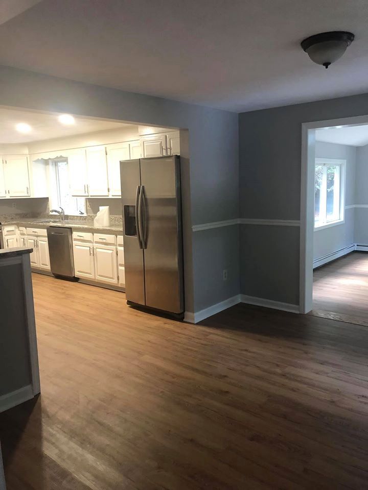 Kitchen with white cabinets, stainless steel refrigerator, and hardwood floors. Gray walls with white trim.