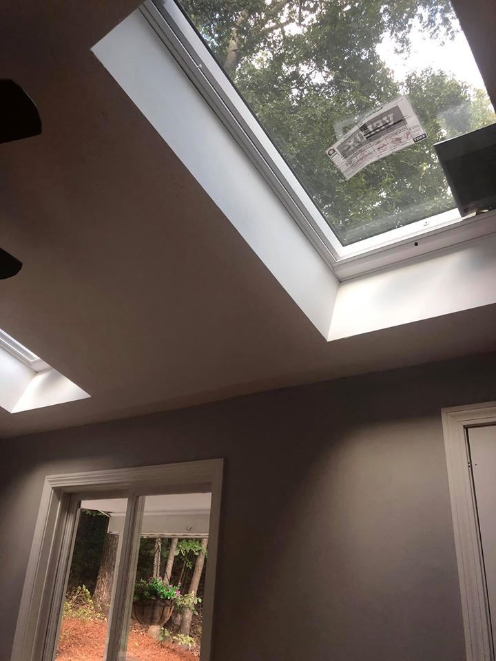 Interior view with skylights, windows, and grey walls. Light streams in, illuminating the room.