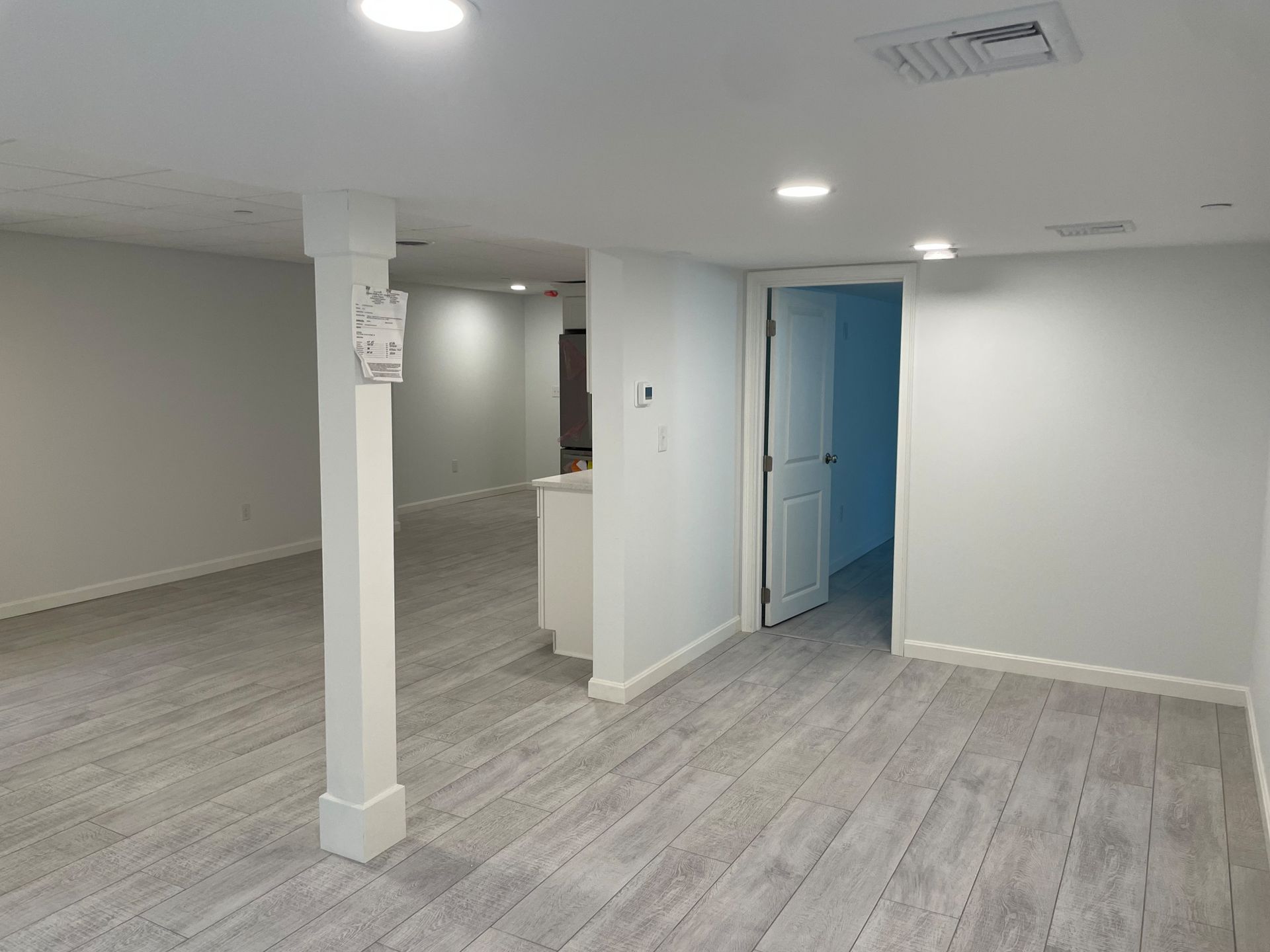 Finished basement with light gray carpet, white walls, recessed lighting, and an open doorway.