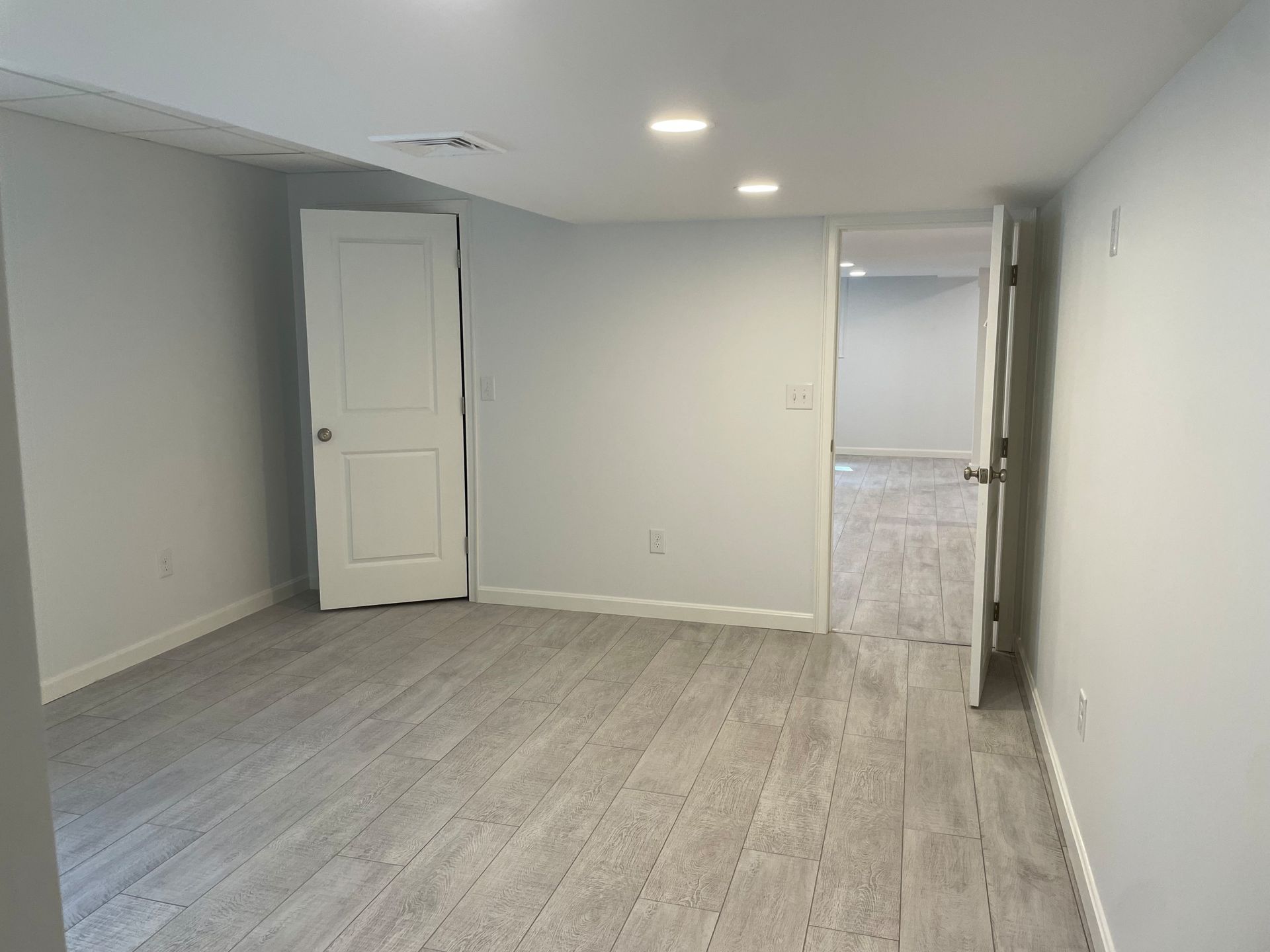 Empty room with light wood-look flooring, white doors, and gray walls, suggesting a newly renovated space.